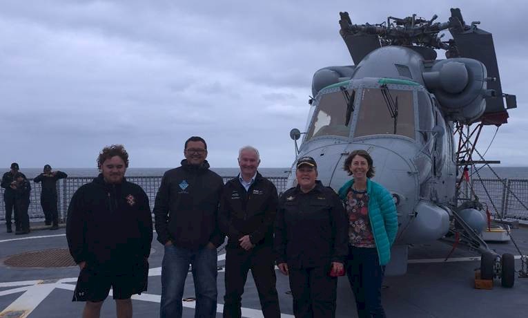 Ali Harrison, Riki Parata, Dr Richard Davies, Commander Bronwyn Heslop, and Vanessa Horwell beside a Sea Sprite helicopter at the end of the voyage. Photo by Hokonui Rūnanga